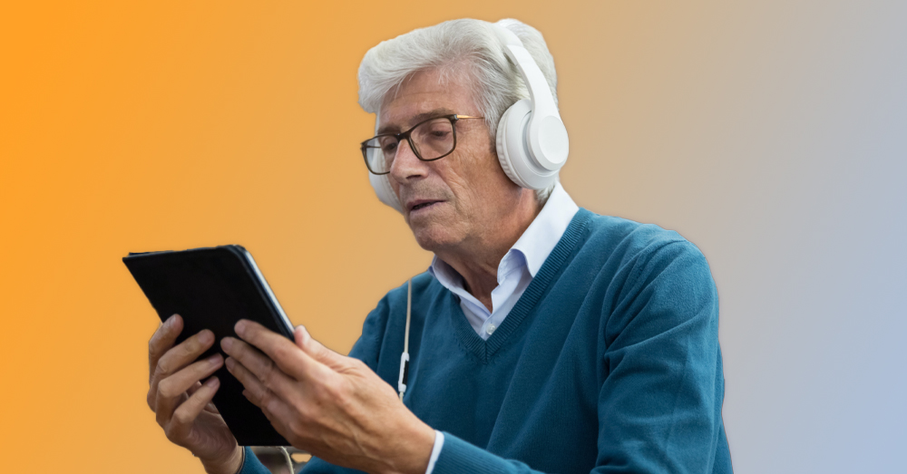 uomo anziano che legge da un tablet aiutato da un lettore digitale